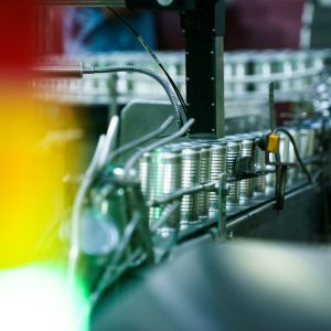 Food cans moving along a conveyor belt in a food manufacturing facility.