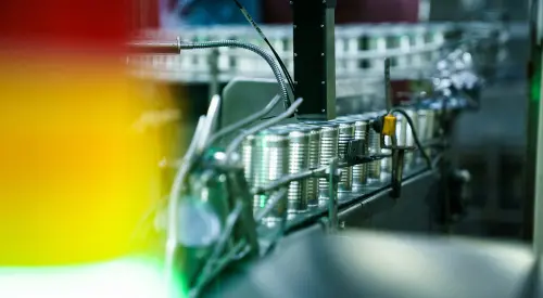 Food cans moving along a conveyor belt in a food manufacturing facility.